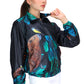 Graphite gray eco-conscious jacket featuring our Capybara friend with a yellow bird on the tip of its nose. Jacket has seven images of the Capybara surrounded by green leaves. The largest Capybara is on the back of the jacket.  Edit alt text